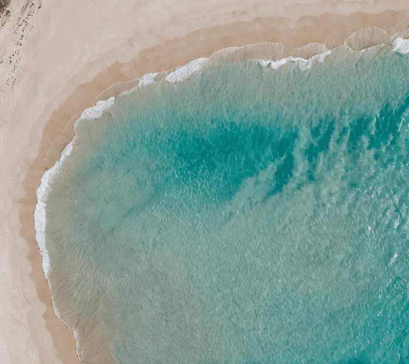 Aerial view of turquoise sea meeting white sandy beach