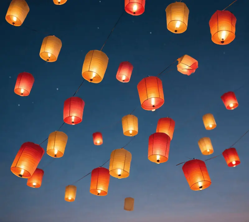 Colorful paper lanterns floating in the twilight sky, representing joyous gatherings.