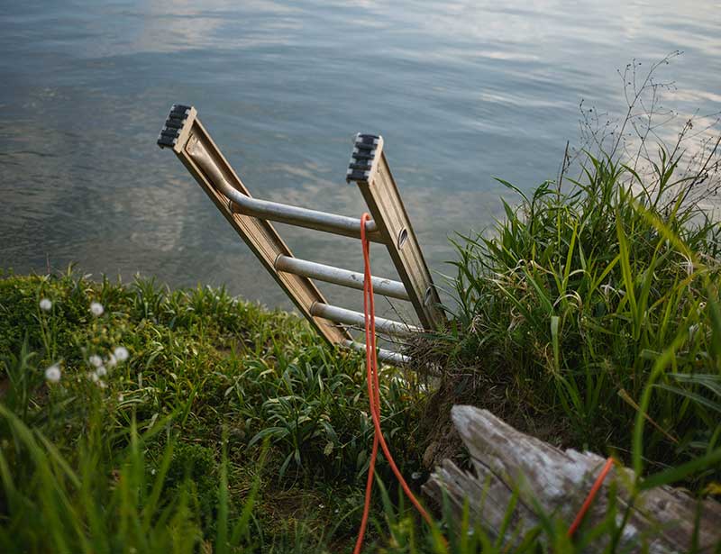 A ladder going down to a lake.