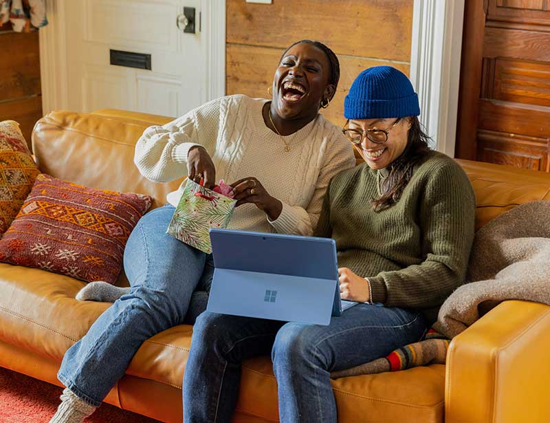 Two friends enjoying a laugh together on a couch,