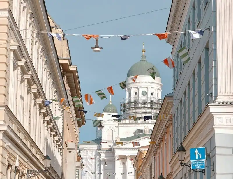 bustling street with flags with view of Helsinki Cathedral during day time