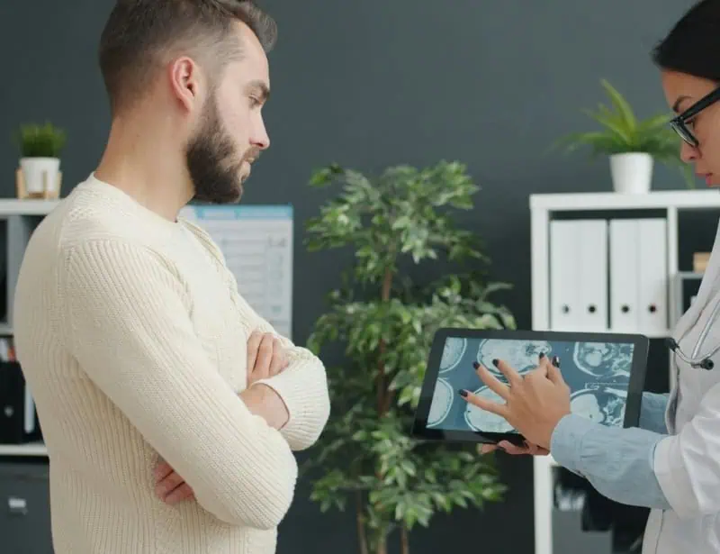 female doctor holding tablet with xray to explain something to male patient