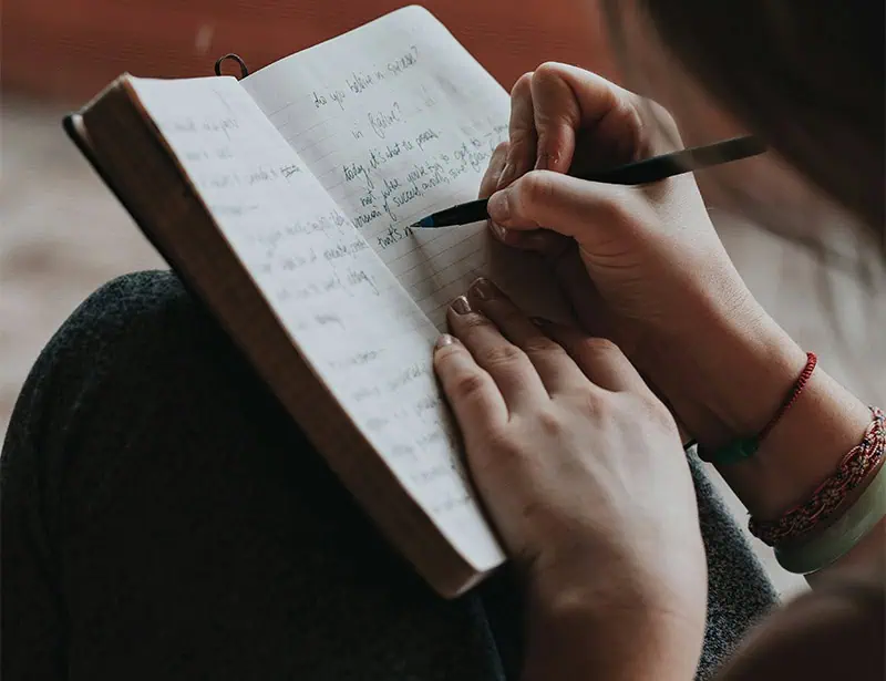 person writing in gratitude journal