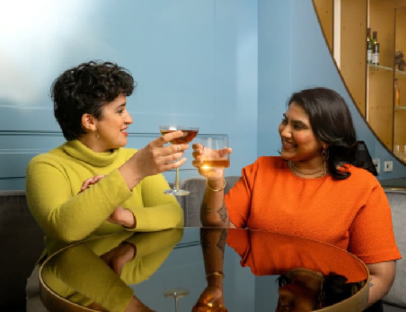 two women clinking glasses with whiskey