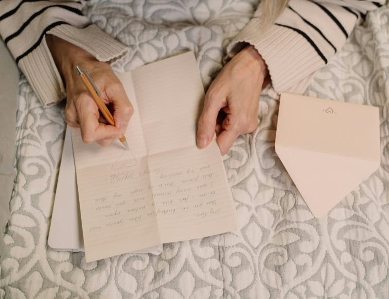 person writing letter with envelope