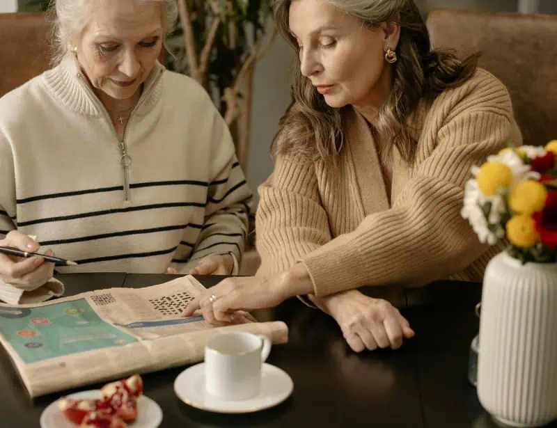 two-elder-ladies-answering-crossword-while-drinking-coffee