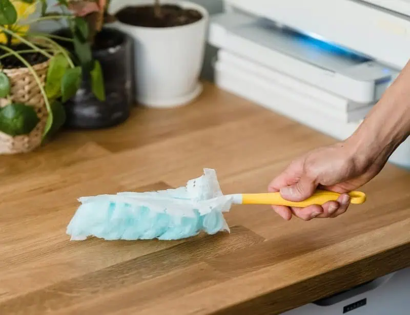 cleaning wooden desk with small broom
