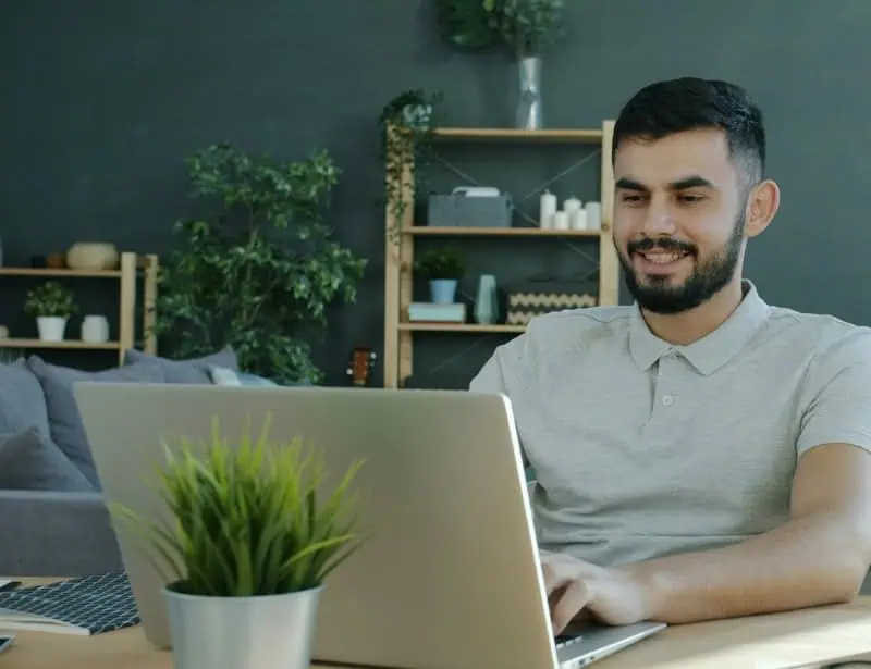 man smiling while surfing web on laptop