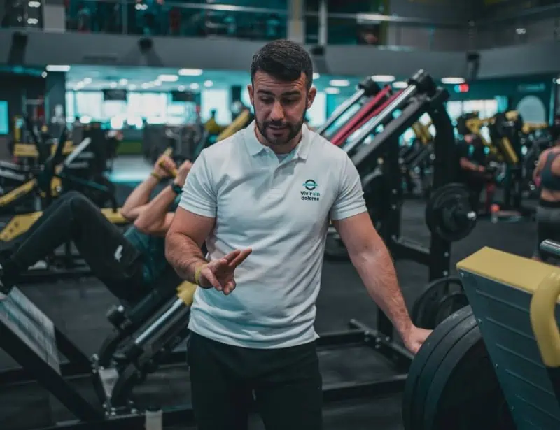 personal trainer in white collared shirt giving instructions in crowded gym