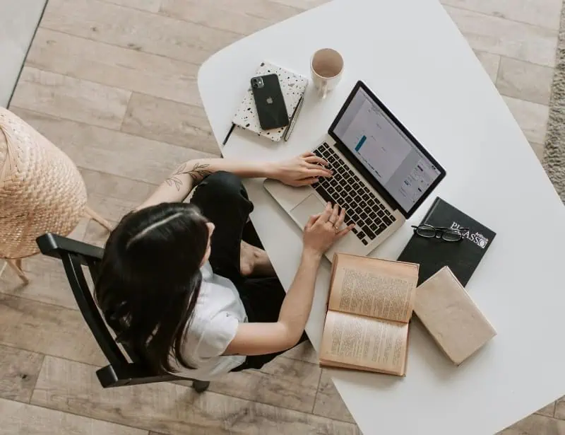 top view of woman researching with laptop and books