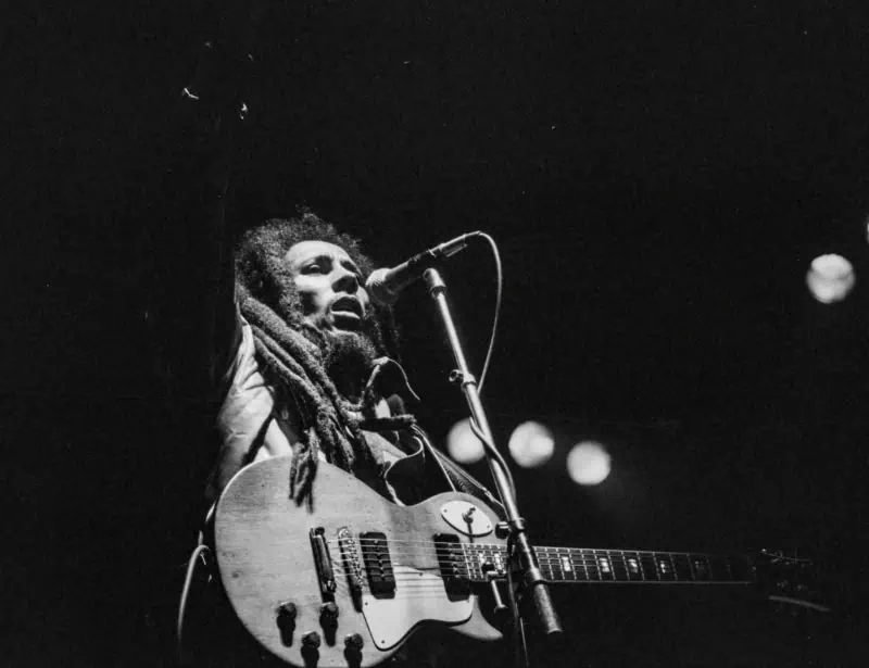 bob marley singing with guitar raising hand during first concert in switzerland in black and white