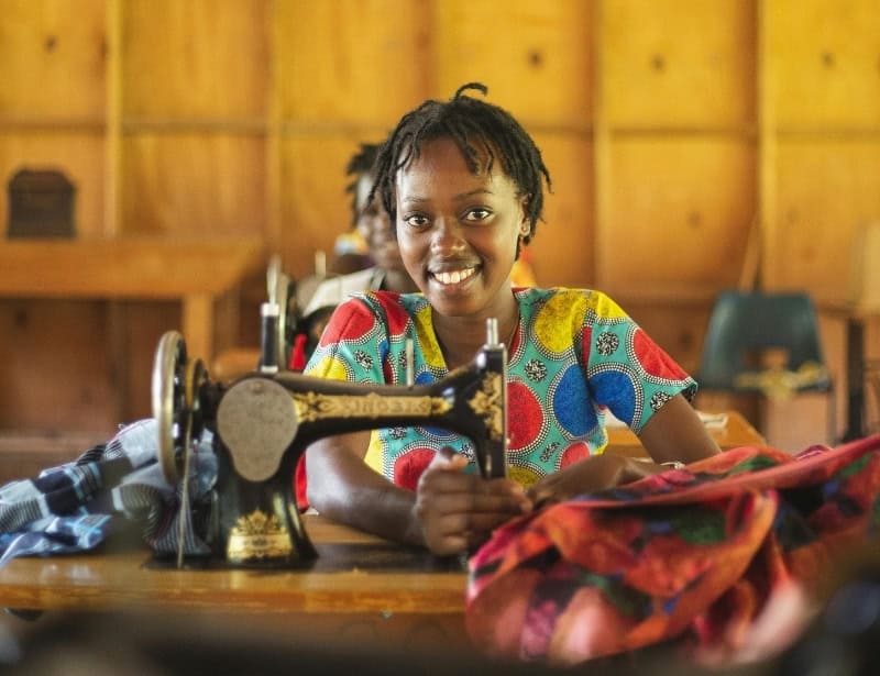 smiling african woman sewing clothes