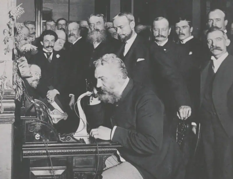 alexander graham bell doing long distance call with telephone in room full of audience