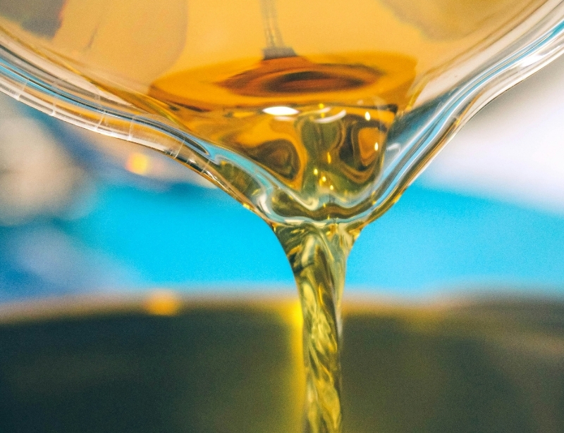 closeup liquid gold oil like substance flowing from glass beaker