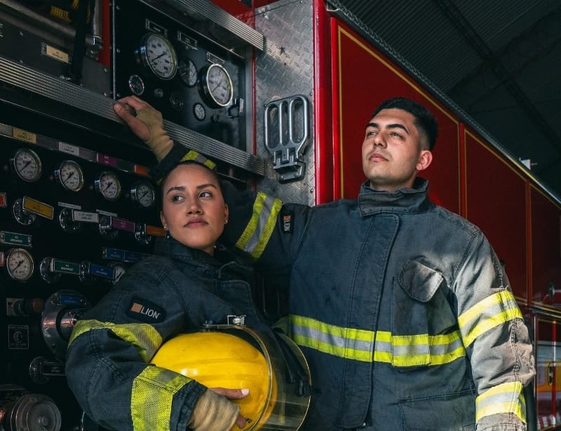 female and male firefighters beside firetruck