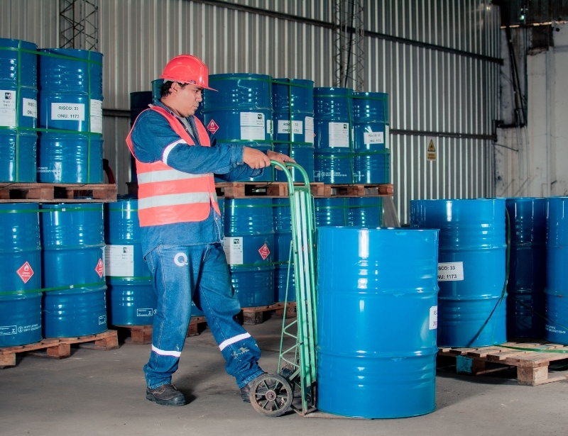 man with complete ppe moving blue barrels in warehouse