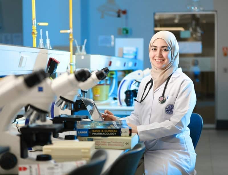 female muslim scientist in laboratory with microscopes