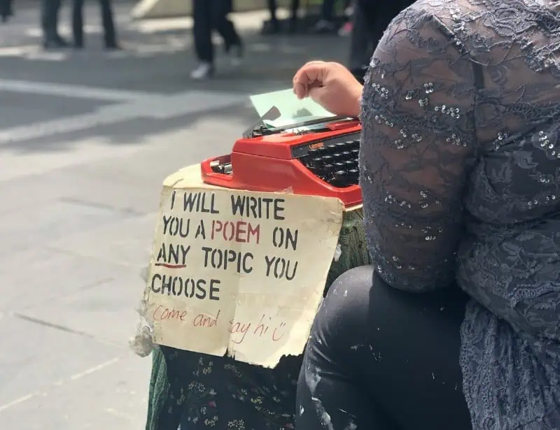 person in public with typewriter offering to write poem on the spot