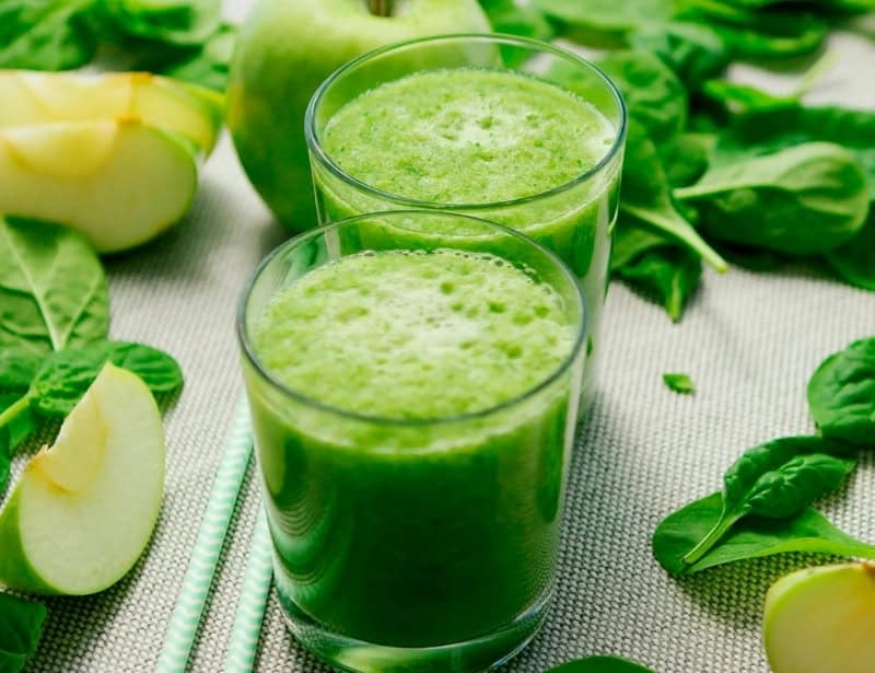 two glasses of green juice with green apple and spinach