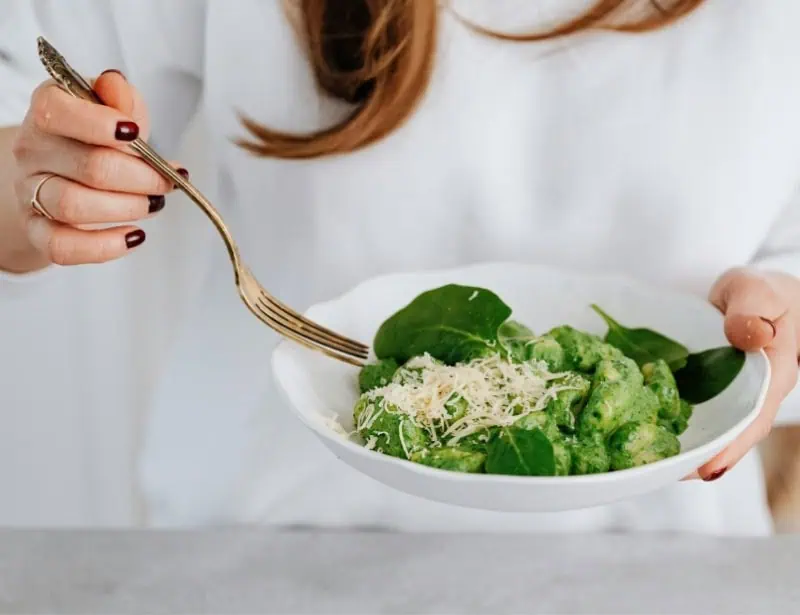 woman using fork to eat spinach salad with cheese