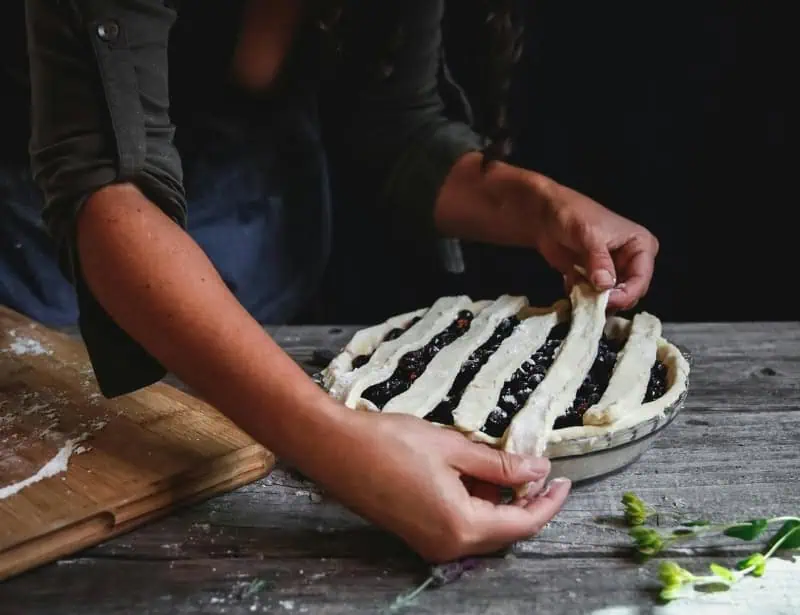 laying dough strips on top of blueberry pie