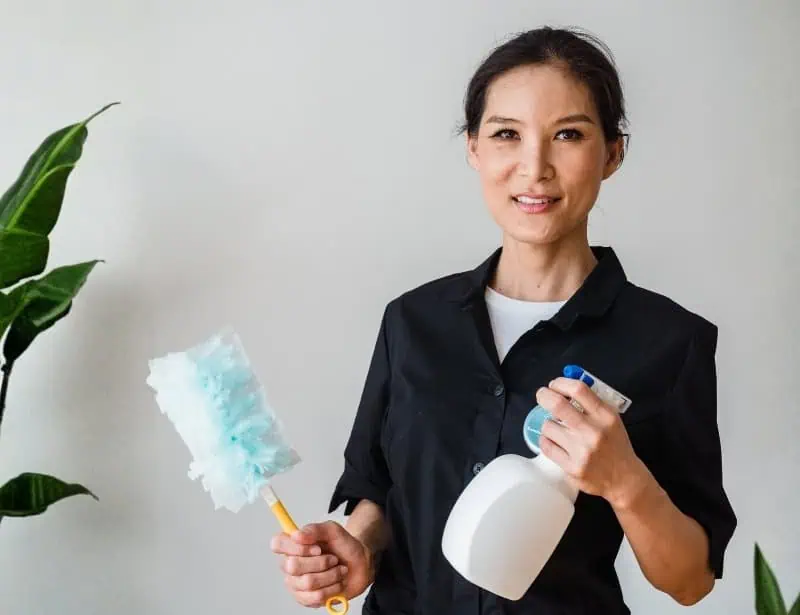 smiling woman holding cleaning materials