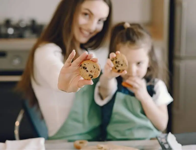 mother and daughter raising cooked choco chip cookies