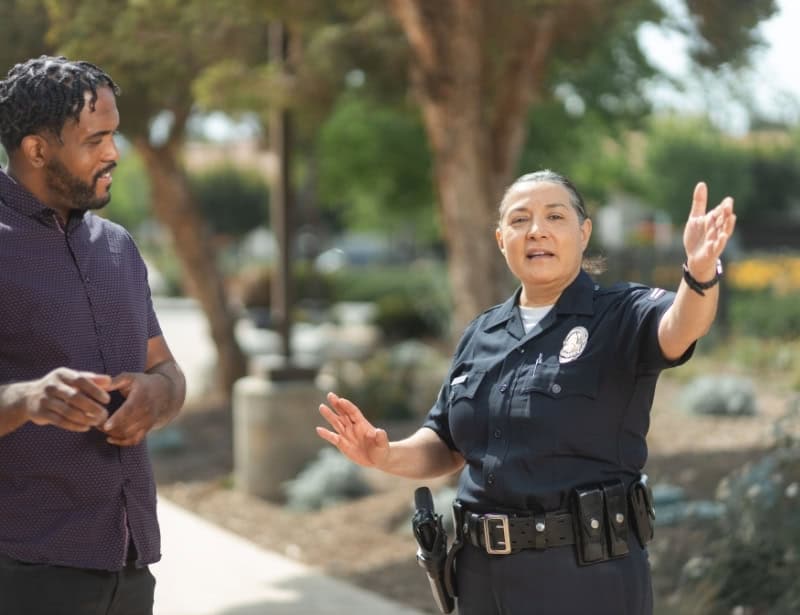 police woman guiding african american man with raised left hand