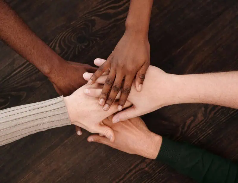 hands of different raced people on top of each other signifying unity 