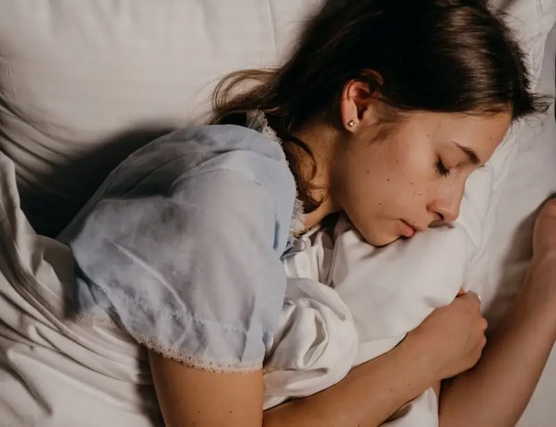 woman sleeping on side white pillows and blanket 