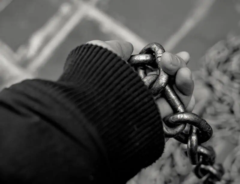 black and white closeup of hand holding chains 