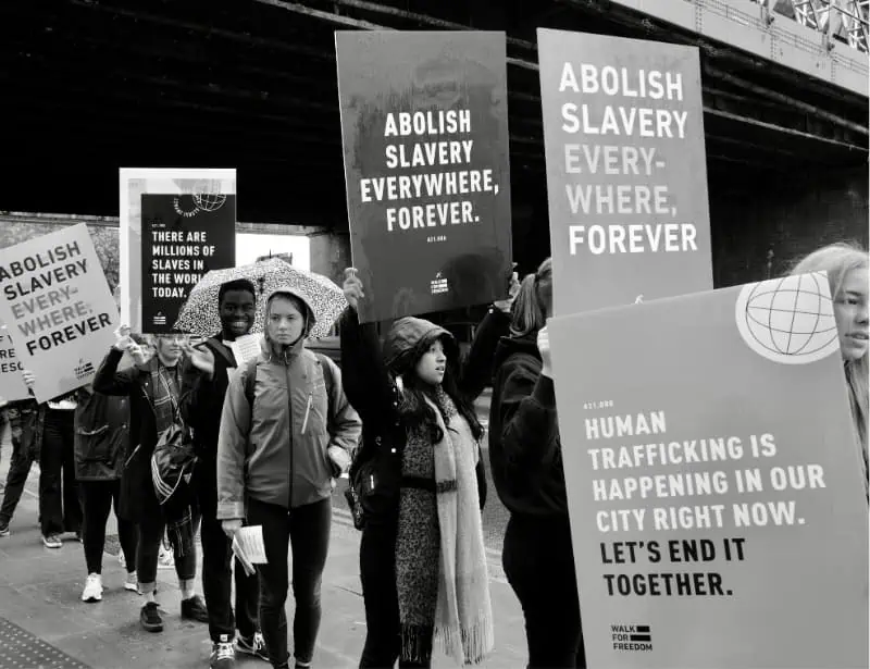monochrome photo of crowd holding signs protesting against slavery 