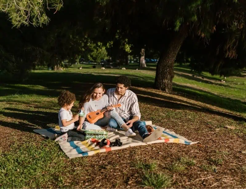 mother father toddler son having a picnic in park during the afternoon