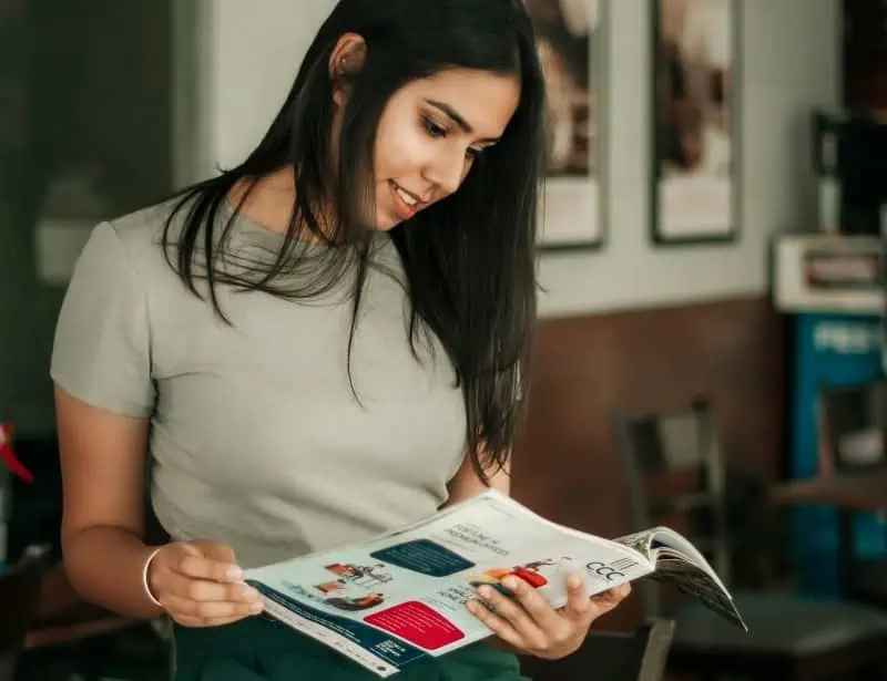 woman smiling while looking at mail catalog magazine