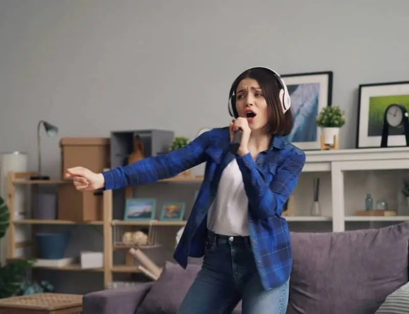 woman wearing white headphones singing and dancing